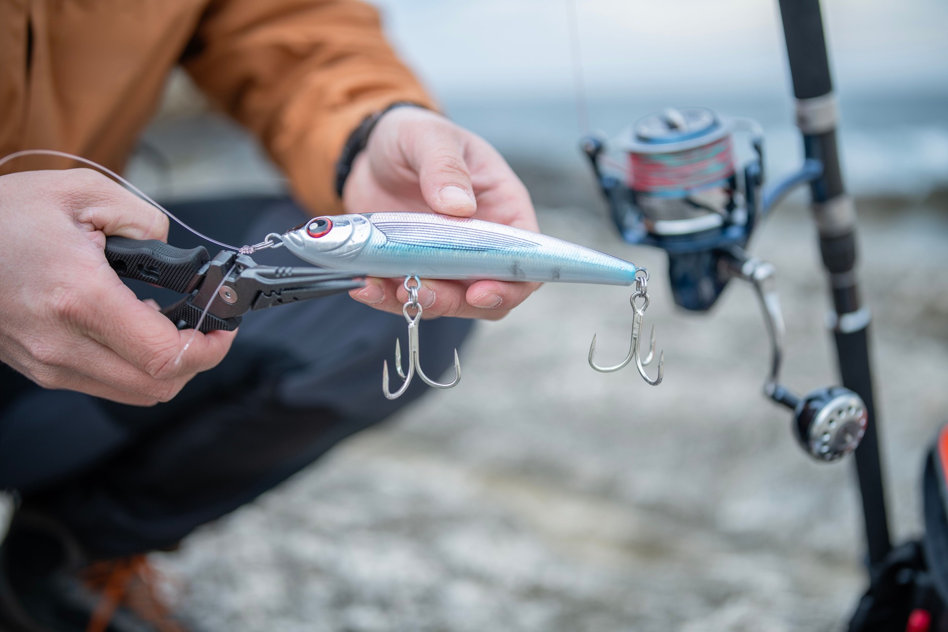 Close-up of man preparing fishing lures for shore fishing.